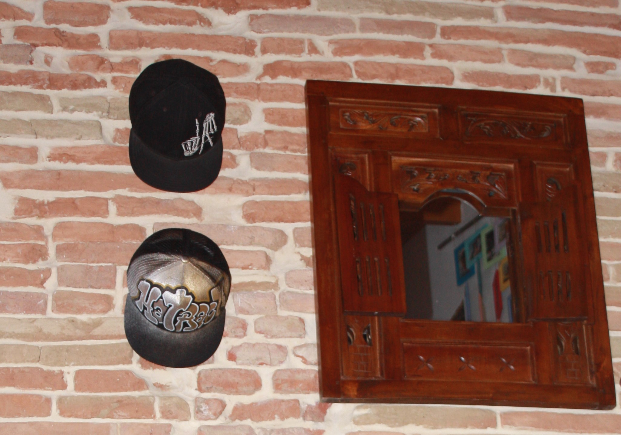 Casquettes exposées sur un mur de brique avec un support Hatrack