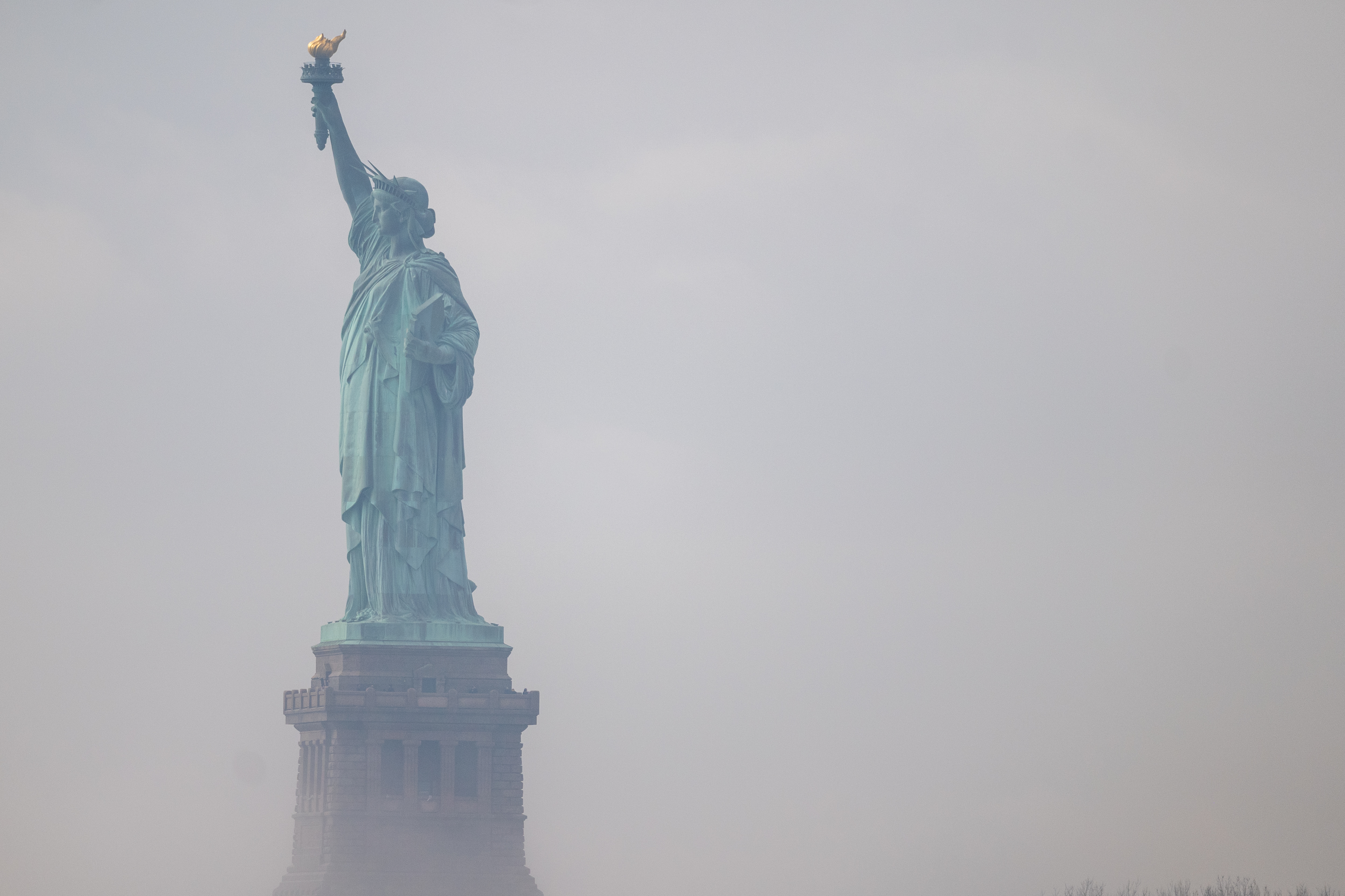 Side profile of the statue of liberty in the fog.