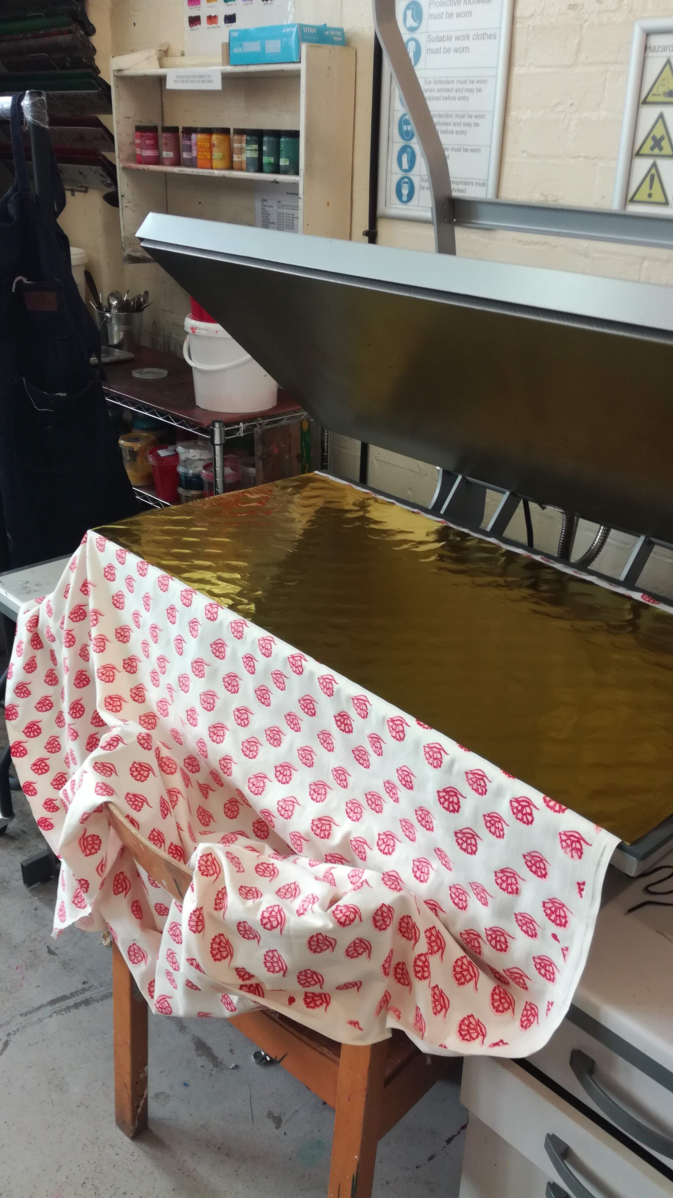 Gold foil being applied on the screenprinted fabric with the heatpress.